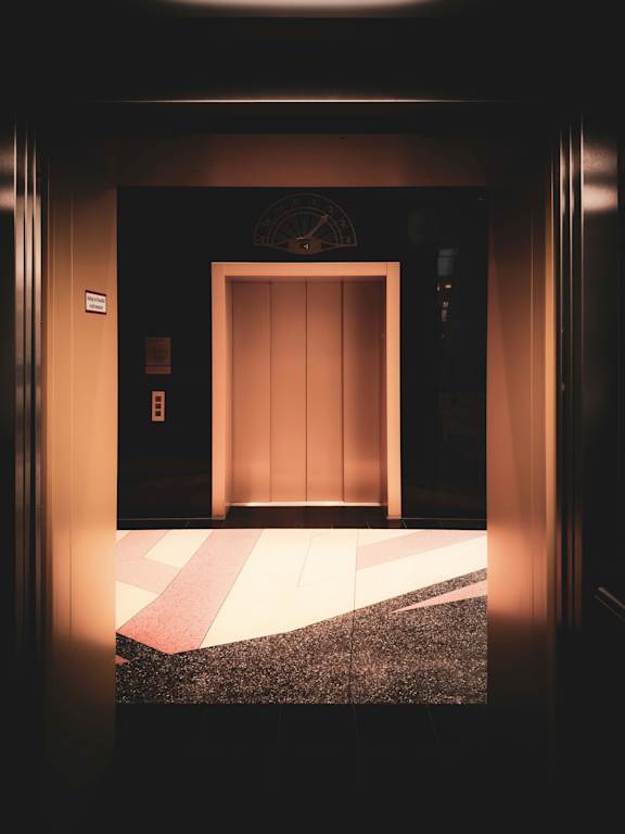 A dark hallway with a light at the end and a door.