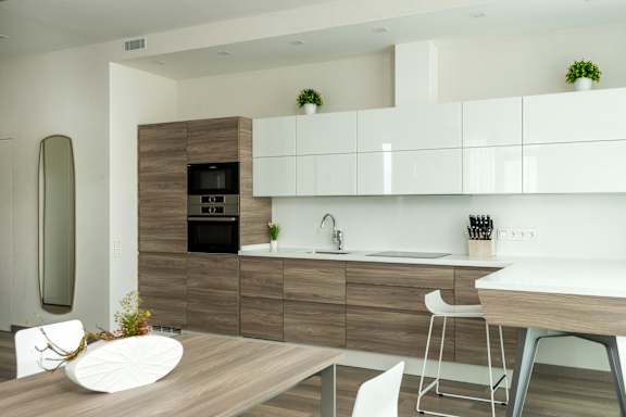 A modern kitchen with a wooden table and white chairs.
