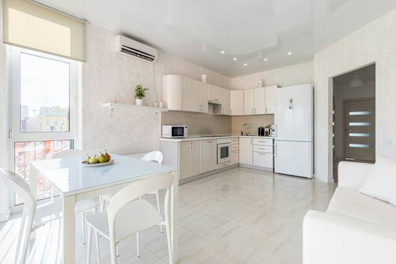 A modern kitchen with white appliances and a dining table with chairs.