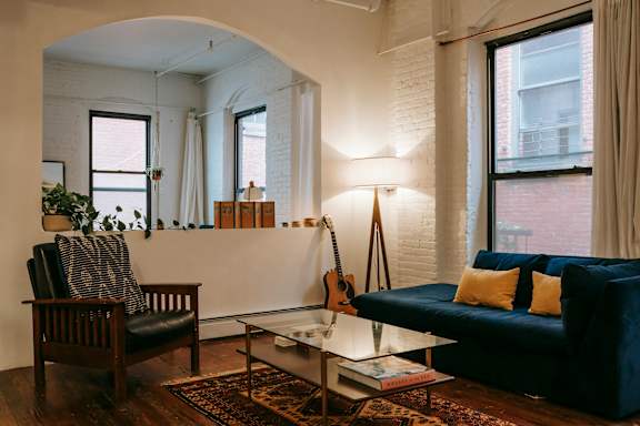 A living room with a guitar on the wall and a blue couch.