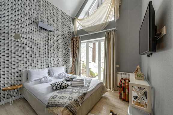 A bedroom with a bed, a television, and a chair.