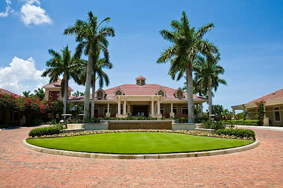A large house with a red roof and a green lawn in front.