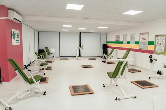 A gym with green chairs and exercise equipment.