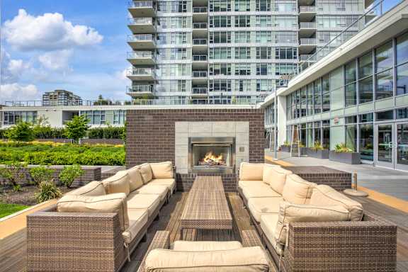 A patio with a fireplace and seating area in front of a modern building.
