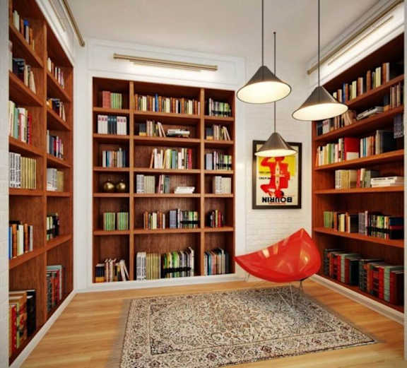A room with a lot of books on the shelves and a red chair in the middle.
