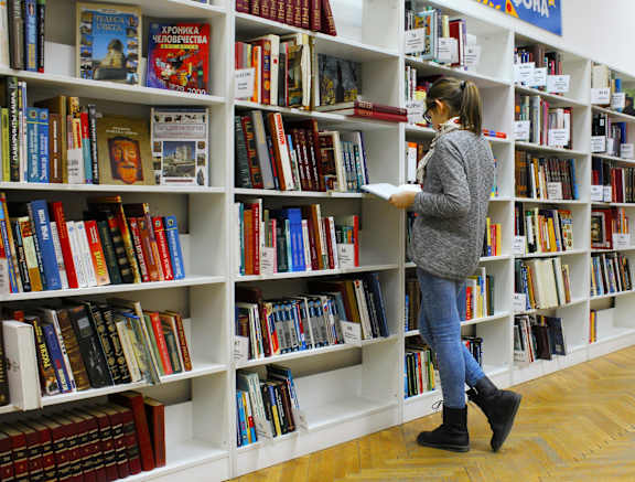 A woman is browsing books in a library.