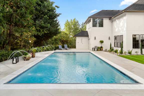 A swimming pool in a backyard with a house in the background.
