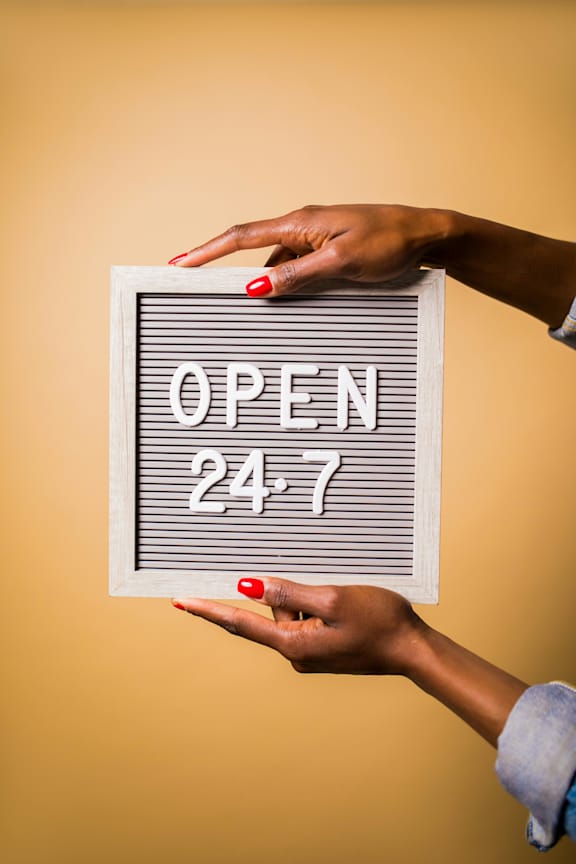 A person holding a sign that says "OPEN 24/7".