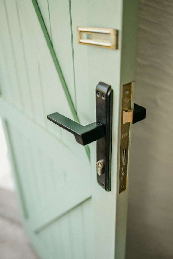 A black handle on a green door.