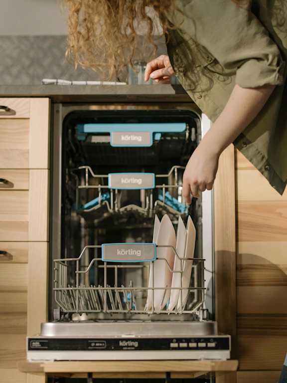 A person is loading dishes into a dishwasher.