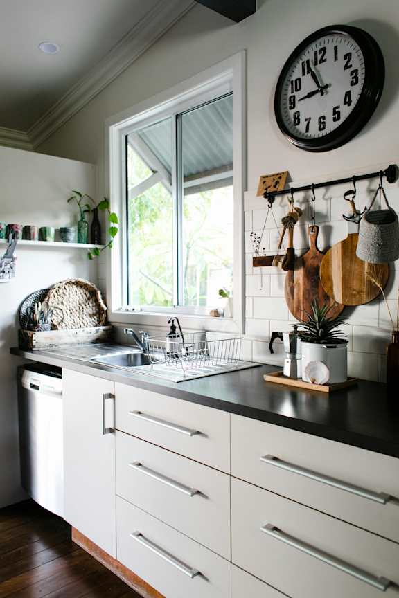 A kitchen with white cabinets and a black countertop with a clock on the wall.