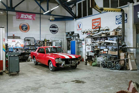 A red and white vintage car is parked in a garage.