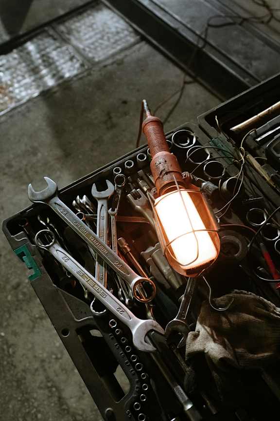 A set of tools is arranged on a black stand with a light bulb in the middle.