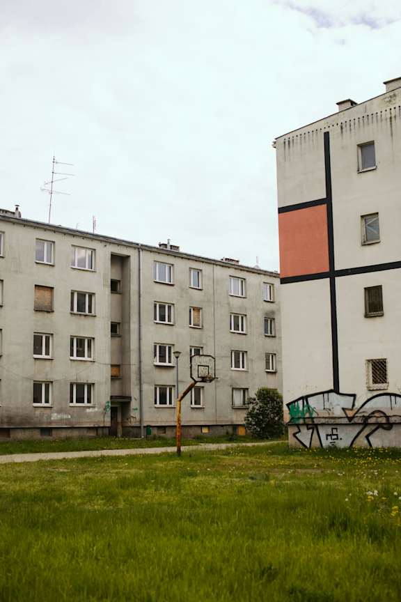 A tall building with a cross design on the side stands next to a smaller building.