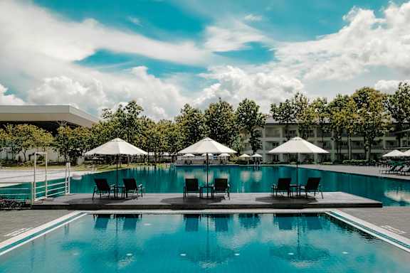 A large swimming pool with lounge chairs and umbrellas.