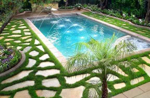A pool surrounded by a green lawn.