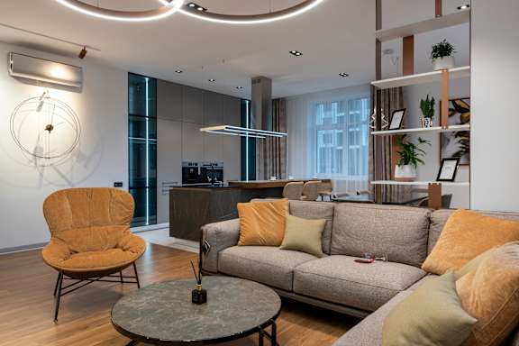 A living room with a grey couch, a yellow chair, and a round table.