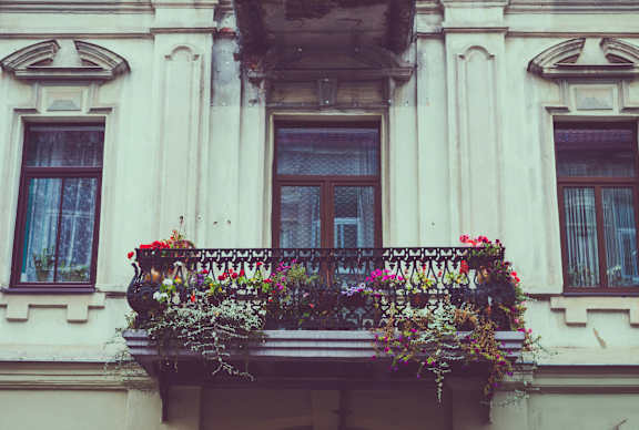 A balcony with a black railing and flowers on it.