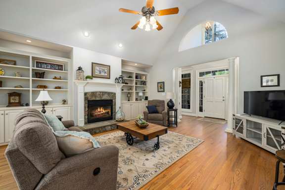 A living room with a fireplace and a ceiling fan.