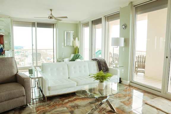 A living room with a white couch and a glass table.