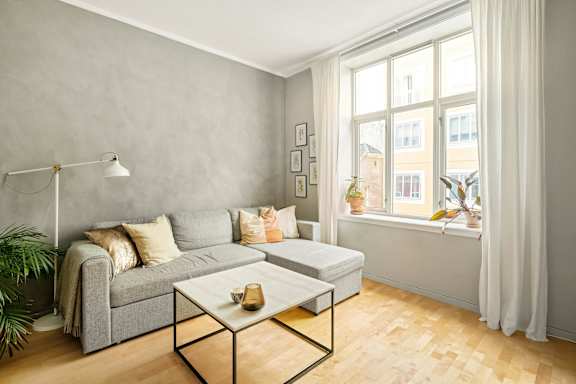 A living room with a grey couch, a white coffee table, and a large window.