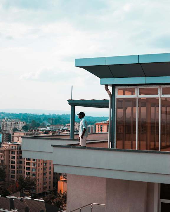 A man stands on a balcony overlooking a cityscape.
