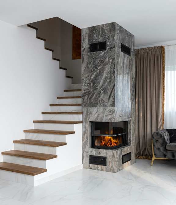 A modern staircase with a fireplace built into the side of the wall.