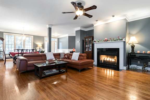 A living room with a fireplace and a ceiling fan.