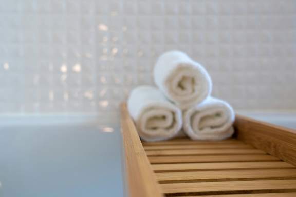 Two white towels are rolled up and placed on a wooden tray.