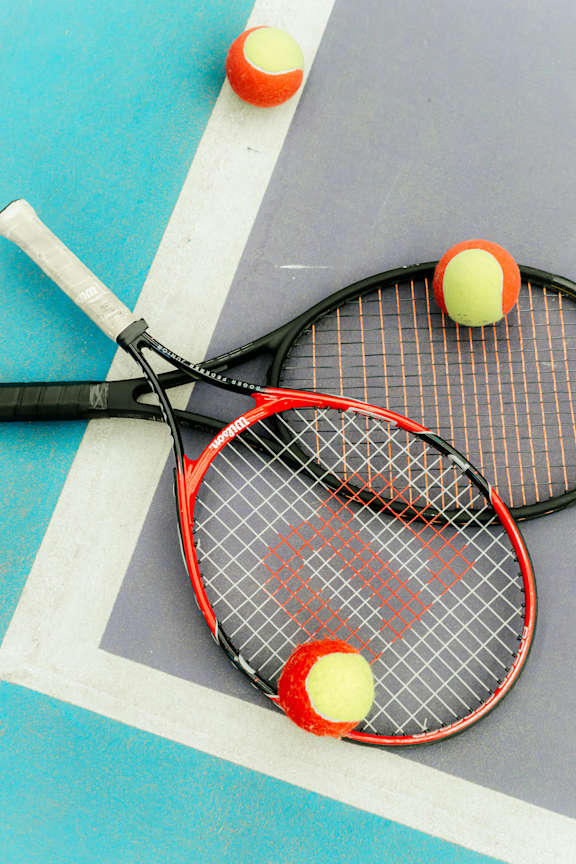 Two tennis rackets and three tennis balls on a court.
