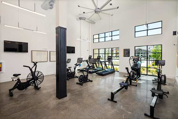A gym with exercise equipment and a fan.