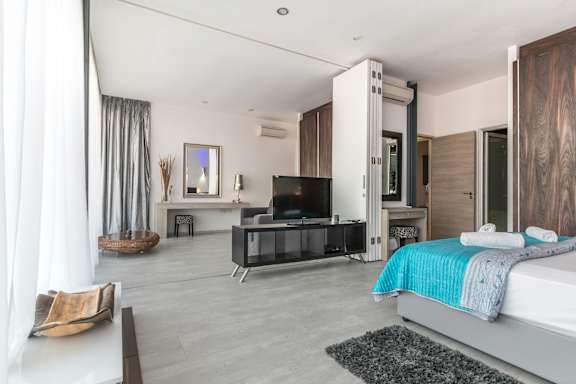 A modern bedroom with a large bed and a television.