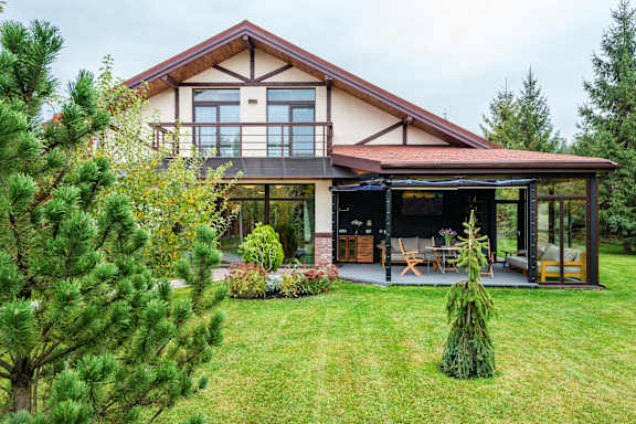 A house with a patio and a tree in front.