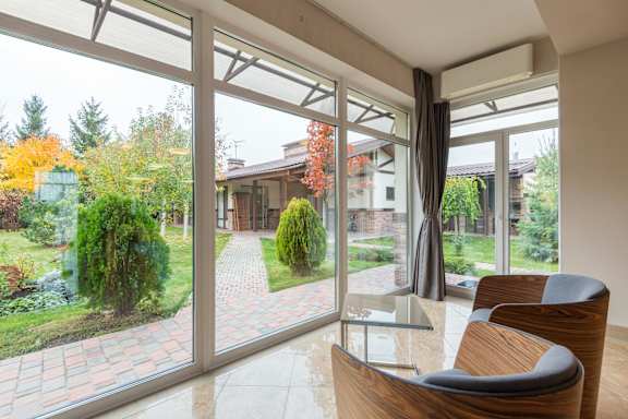 A modern house with a glass table and chairs in the foreground.