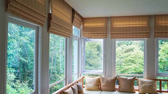 A room with a window seat and a view of trees.