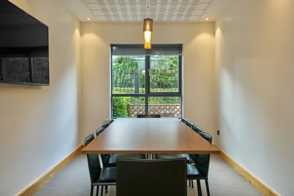 a meeting room with a large table and chairs in front of a window