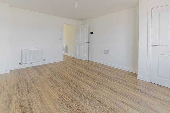 A room with wooden flooring and white walls.