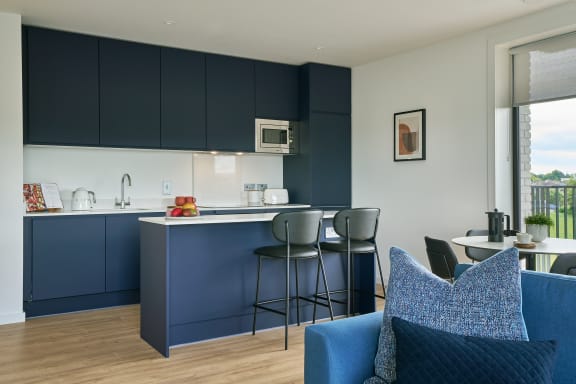 a kitchen and living room with blue cabinets and a white counter top and blue chairs