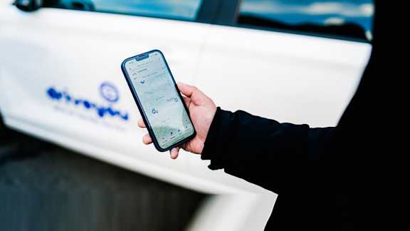 A person is holding a smartphone with the DriveYou application open.