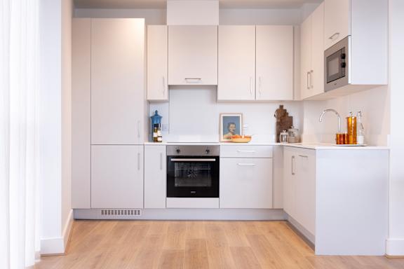 A modern kitchen with white cabinets and a wooden floor.