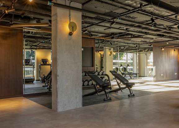 A gym with a row of benches and a weight machine.