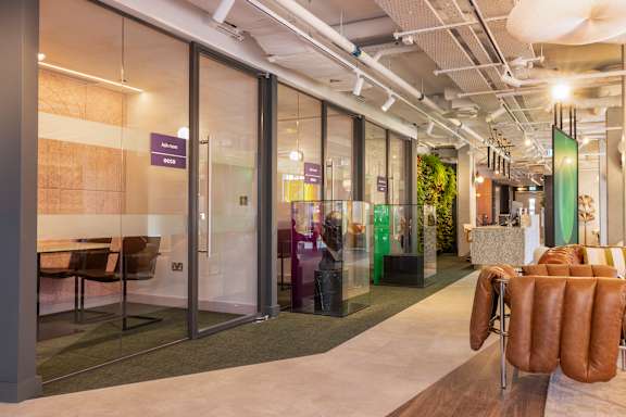 A modern office space with glass walls and leather chairs.