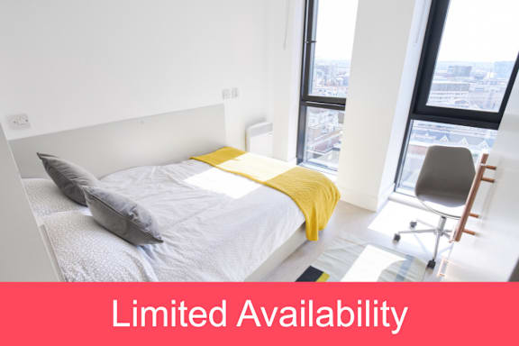 Floor Plan  A bedroom with a bed, chair, and window overlooking a cityscape.