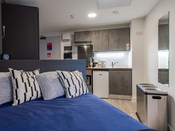 Floor Plan  a bedroom with a bed and a kitchen in the background