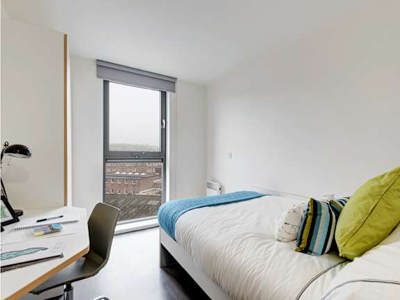 Floor Plan  A bedroom with a bed, desk, chair, and a window overlooking a cityscape.