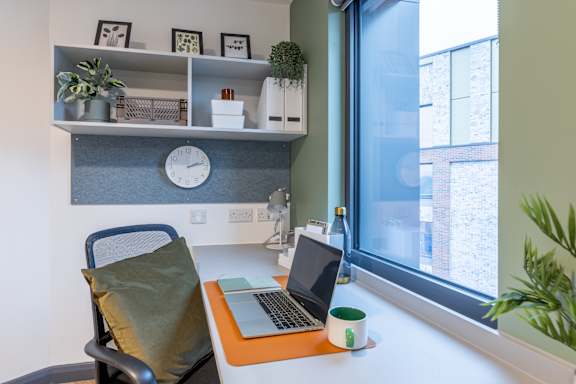Floor Plan  A laptop is on a desk with a green mug and a plant.