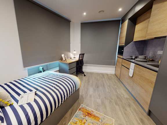 Floor Plan  A bedroom with a bed, desk, and kitchenette.