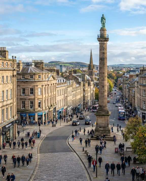 A city street with a tall column in the middle of it.