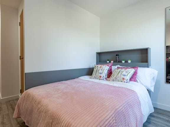 Floor Plan  A bed with a pink comforter and two pillows with floral patterns.