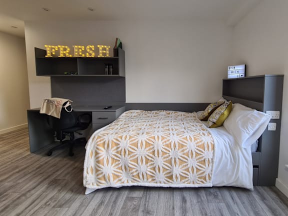 Floor Plan  A bedroom with a bed, desk, and a shelf with a sign that says &quot;FRESH&quot;.